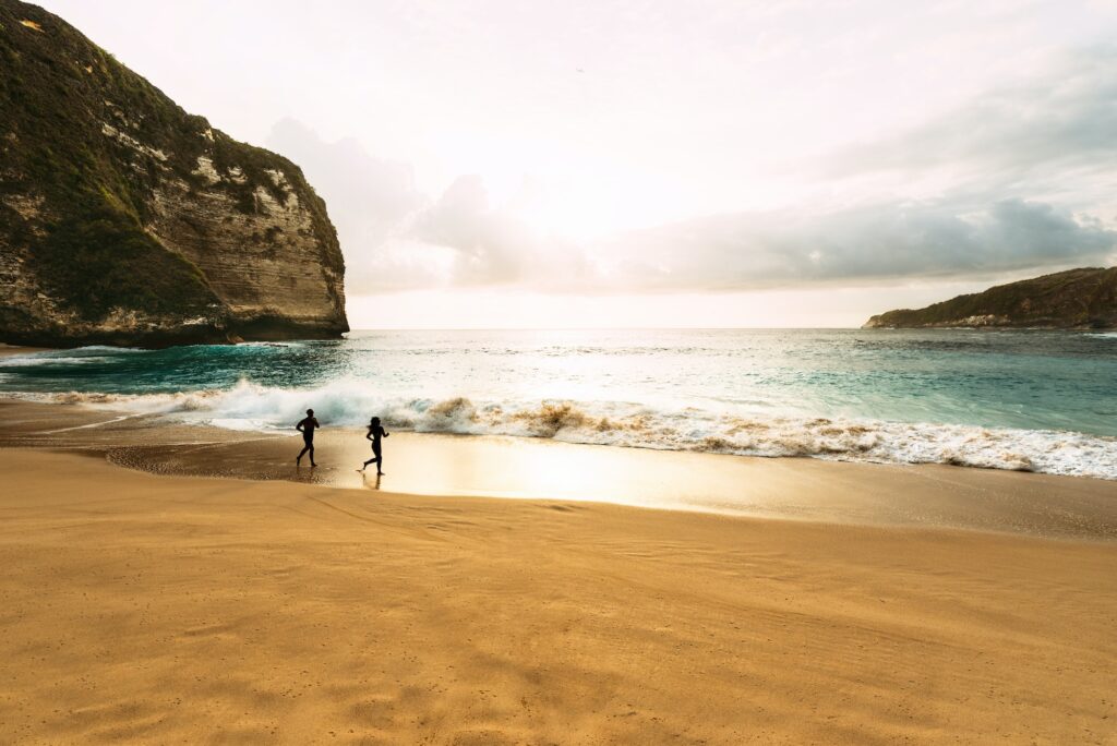 Silhouette of a couple running on the beach at sunset